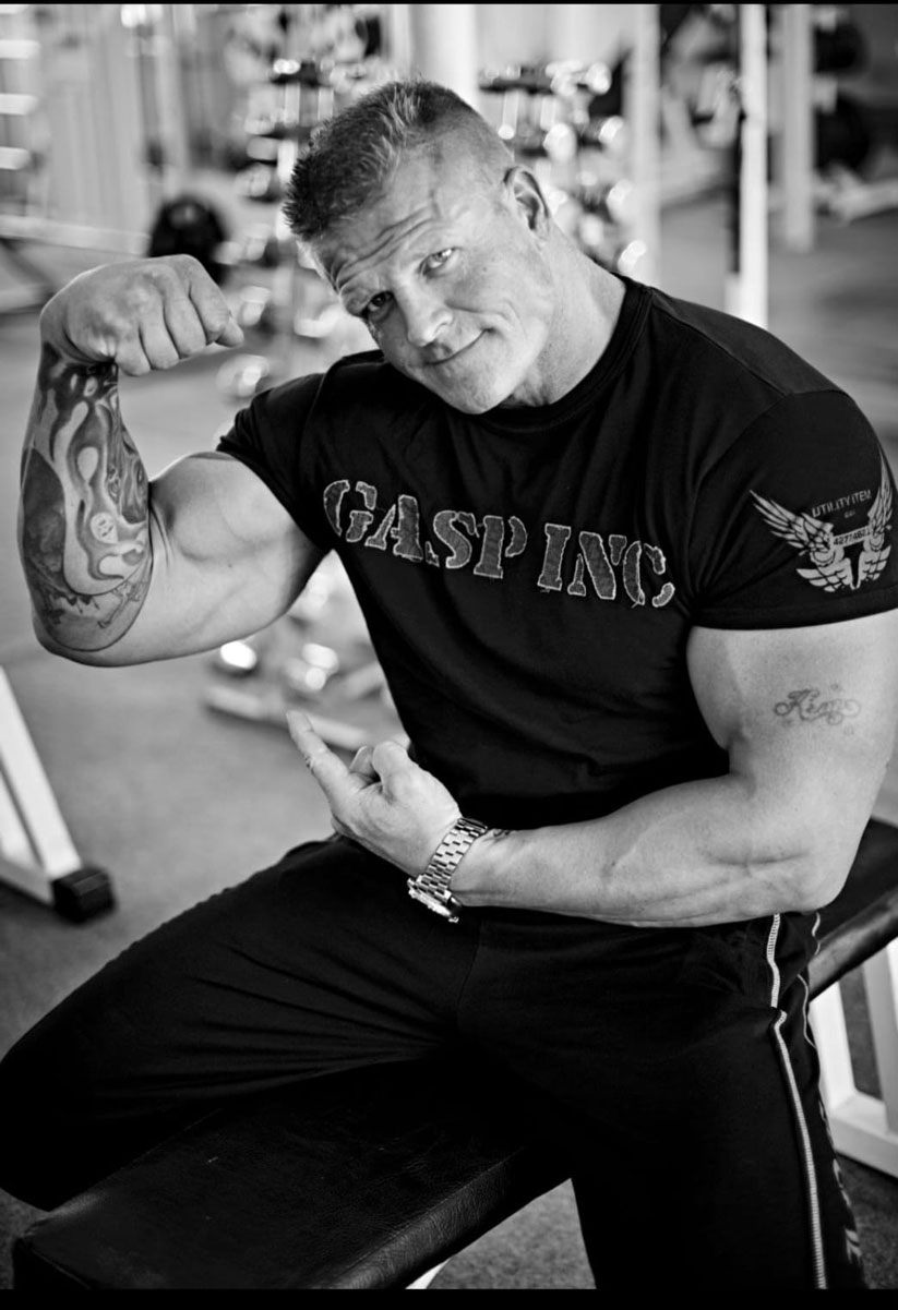 Træneren bøjer sin muskuløse arm.